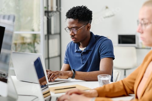 Preview: Young programmer typing on laptop at office