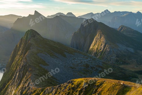 Preview: View from above, two people and a tent perched on a ridge in the dramatic peaks of Senja Island,