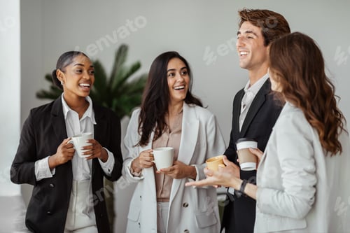 Preview: Group of multiethnic colleagues standing with cups of coffee and talking while taking coffee break