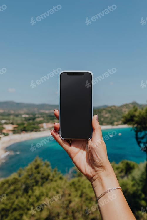 Preview: Woman holding a phone at the beach