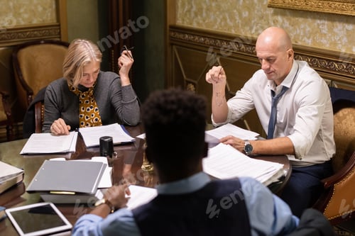 Preview: Three interracial co-workers looking through juridical documents