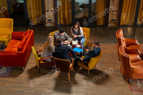 Preview: top shot in large beautiful hall office employees sitting on yellow chairs discuss a deal
