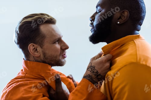Preview: side view of multiethnic prisoners threatening each other and holding collars