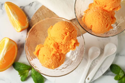 Vista previa: Balls of tasty orange sorbet in dessert bowls, fresh fruit and mint on white marble table, flat lay