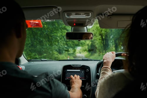 Preview: Rearview shot of a young couple sitting in their car ready to depart on their roadtrip