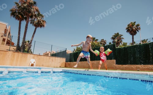 Preview: Two kids run and jump to the swimming pool at the sunny summer day