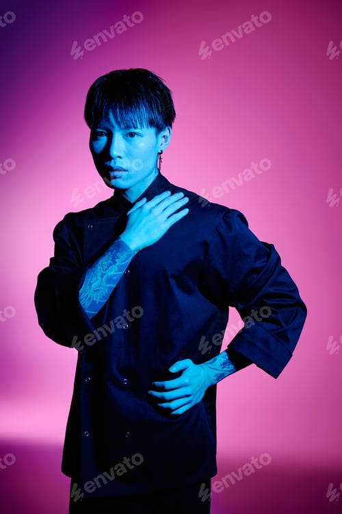 Preview: Stylish young asian man with tattoos posing confidently against vibrant background
