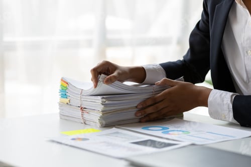 Preview: Businesswoman working on stacks of paper files.