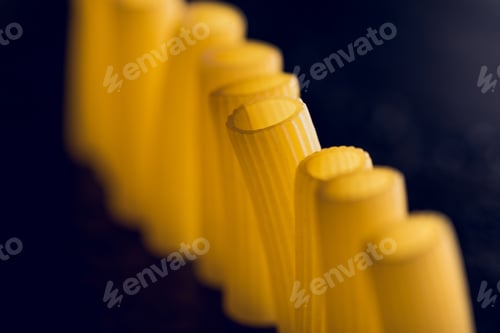 Preview: raw pasta standing in row on black concrete table