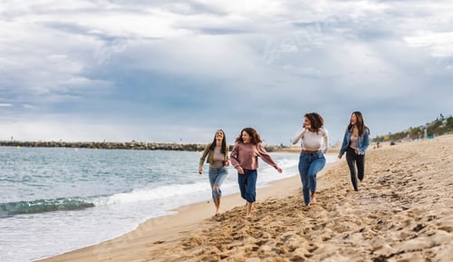 Preview: open shot of diverse ethnic friends running free empowered on the beach
