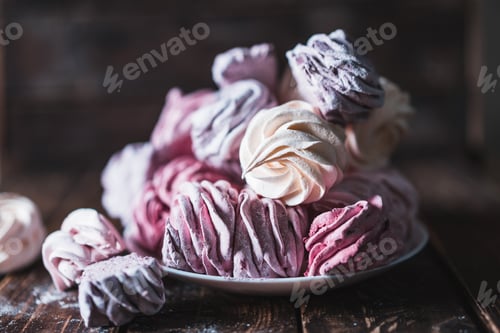 Preview: Appetizing multi-colored zephyr on a plate on a wooden table.
