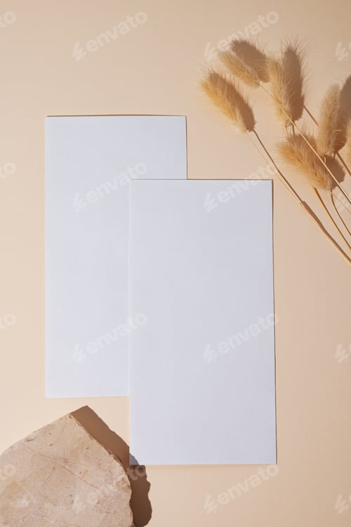 Preview: White empty envelope with dried flowers on a beige background with texture stone.