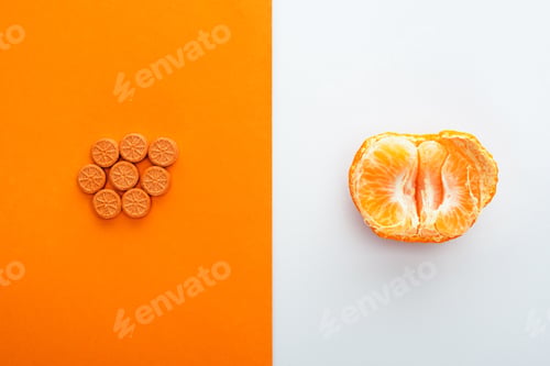 Preview: Top View of Pills And Mandarin Half on White And Orange Background