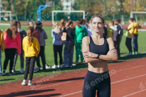 Preview: A female physical education teacher at school smiles and looks at the camera, an athlete trainer on