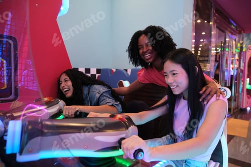 Preview: Young women having fun playing arcade racing game together