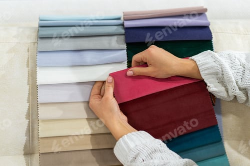 Preview: The woman chooses the fabric on the sofa. Textile industry background. Tissue catalog