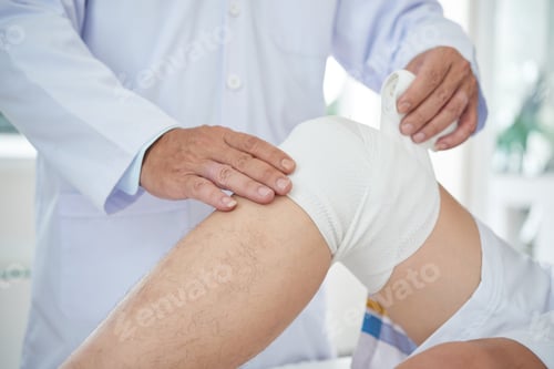 Preview: Crop doctor bandaging knee of patient