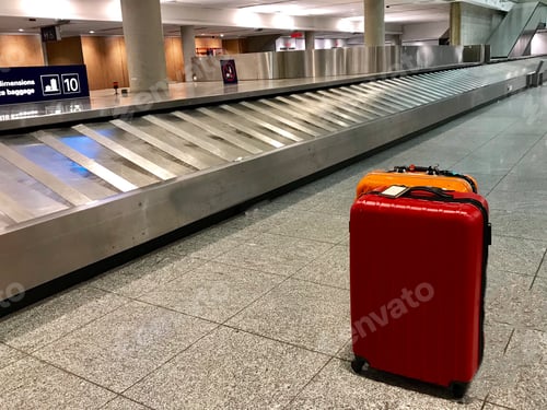 Preview: Red and orange suitcases at an airport alone with no other suitcases by a carrousel minimalist