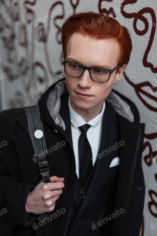 Preview: handsome red-haired hipster guy with glasses in fashionable clothes with a coat
