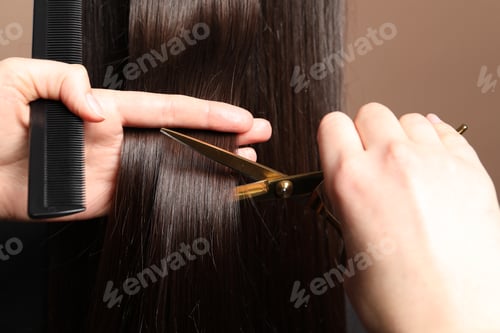 Preview: Hairdresser cutting client's hair with scissors on light brown background, closeup