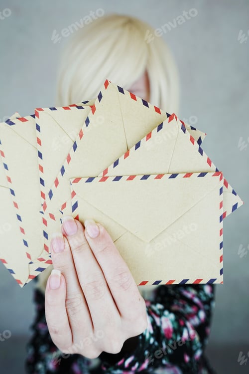 Preview: Young woman holding a paper envelope