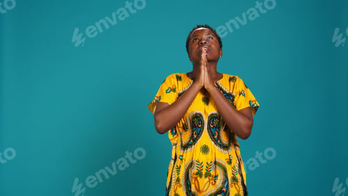 Preview: Religious optimistic girl praying to God for good fortune in studio