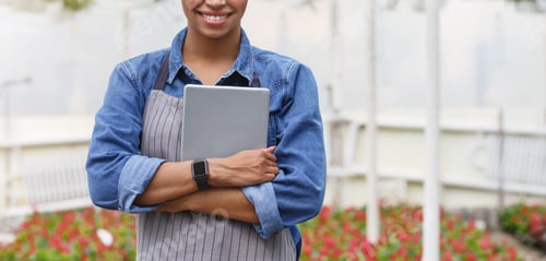 Preview: Smart greenhouse concept. African american smiling girl presses tablet to chest