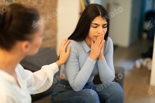 Preview: Female psychologist calming sad spanish lady, doctor consulting patient in clinic office interior