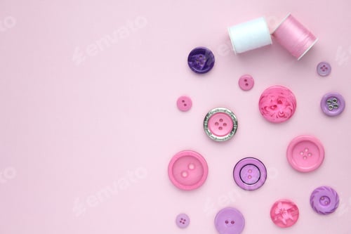 Preview: Sewing items flat lay style - pink and purple buttons and spools of cotton thread