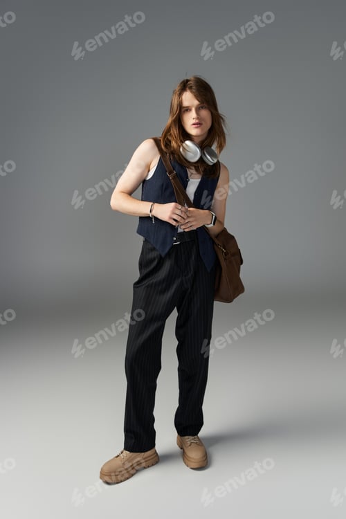 Preview: Stylish young man in fashionable attire poses confidently against a minimalist backdrop