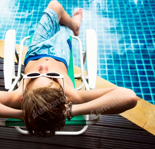 Preview: Young caucasian boy enjoying sunbathing by the pool