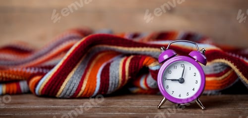 Preview: Retro alarm clock and scarf on wooden table.