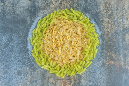 Preview: Bow tie and fusilli pasta in the bowl, on the marble background