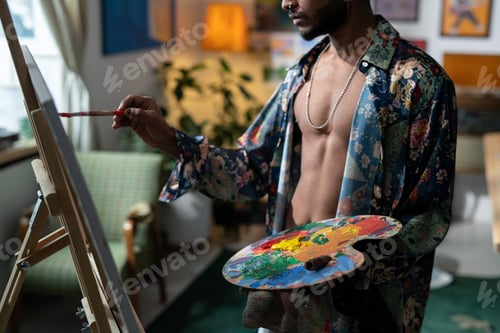 Preview: Middle section of young sexy man with color palette painting on easel