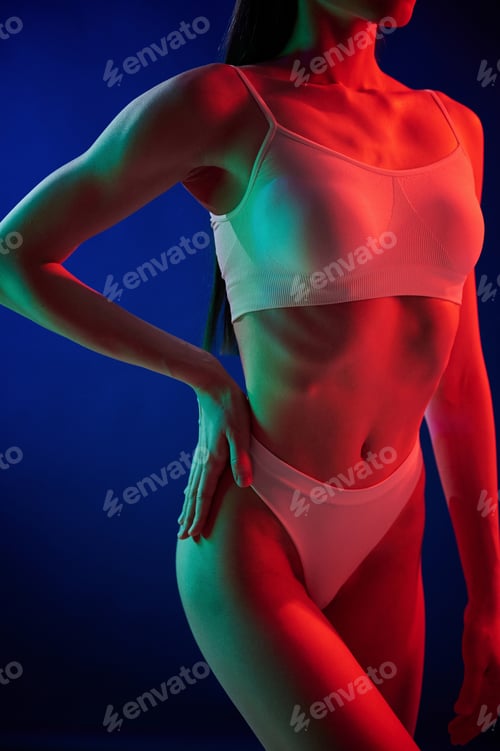 Preview: Close up view. Young woman in underwear is in the studio with neon lights