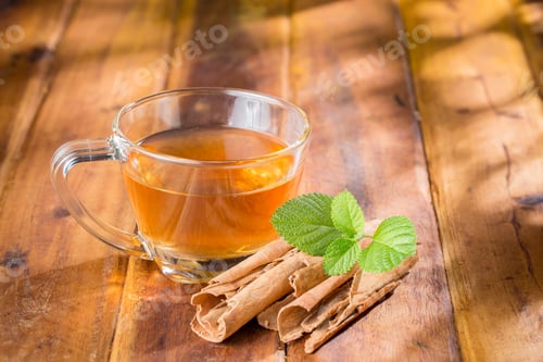 Preview: Cinnamon tea in glass cup, on wooden surface, royalty free