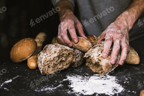 Preview: Baker man holding a rustic organic loaf of bread in his hands