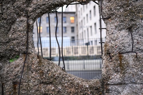 Preview: Hole in Broken Berlin wall and walking person against