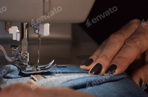 Preview: Seamstress using sewing machine to hem jeans pants