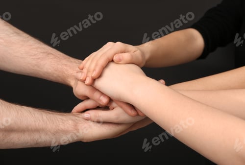 Preview: Young people putting their hands together on dark background, closeup
