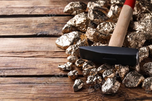 Preview: Pile of gold nuggets and hammer on wooden table, closeup. Space for text