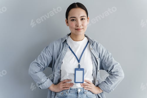 Preview: Pretty woman with name tag on gray background. Close view, blank name tag.
