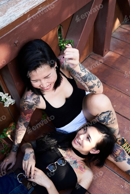 Preview: Tattooed lesbian couple laughing and having fun on wooden bridge
