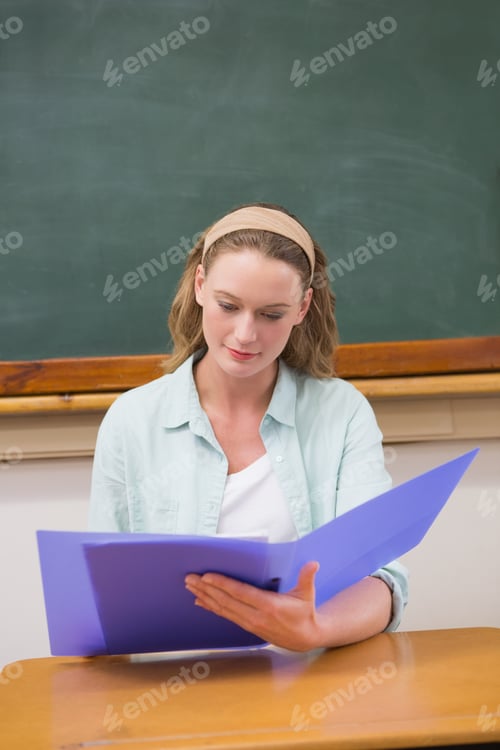 Preview: Teacher Reading Papers At Her Desk At Elementary School