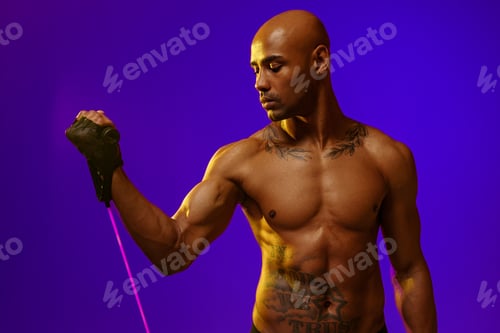 Preview: Sporty man performs exercises with expander on studio background. Strength and motivation