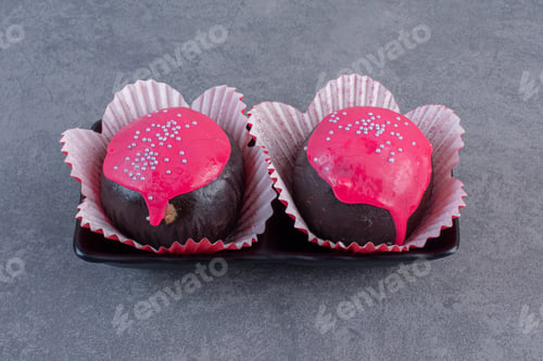 Preview: Chocolate balls with pink glaze on dark plate