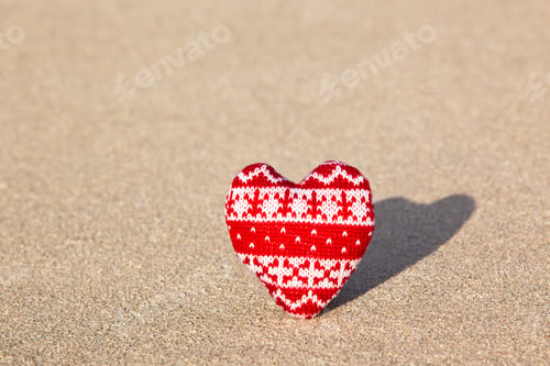 Preview: red knitted heart on sea sand