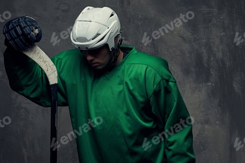 Preview: Hockey player wearing black protective uniform holds a hockey stick on a gray background.