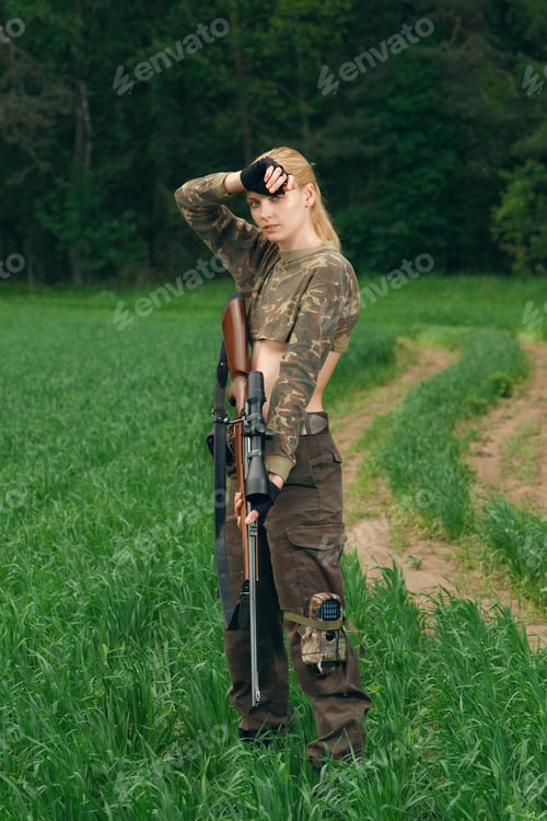 Preview: Attractive hunter girl with hunting carbine looking out the trophy