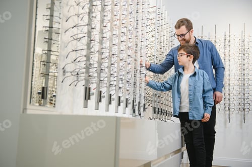 Preview: Dad and son choose new stylish glasses in an optical store. Vision care concept